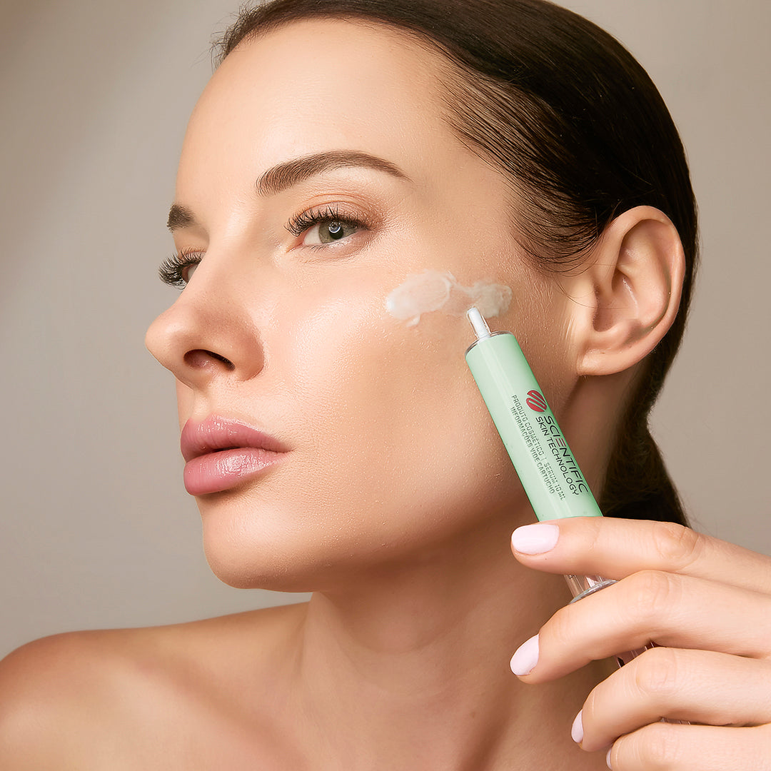 Person applying skincare product to their cheek using a green tube applicator.